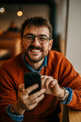 Wall Mural - Male nerd with glasses sitting in the office and using a phone.