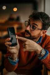 Wall Mural - Male nerd with glasses sitting in the office and using a phone.