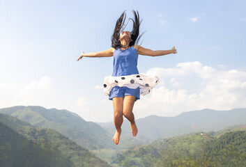 Cheerful woman jumps high on the background of mountains