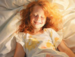 A young girl tucked into a warm bed smiling happily through sleepy eyes as a ray of sunshine spreads across her .