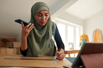 Wall Mural - Tailor listening to voice message from client and drawing sewing pattern
