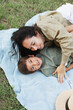 © Dina - Mother and son smiling in the park on blue blanket and  green grass. Happy family in summer, enjoying life. Dark haired and tanned parent and kid on summer vacation.