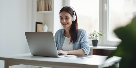 Canvas Print - A young woman is talking to someone and taking notes during an online conversation.