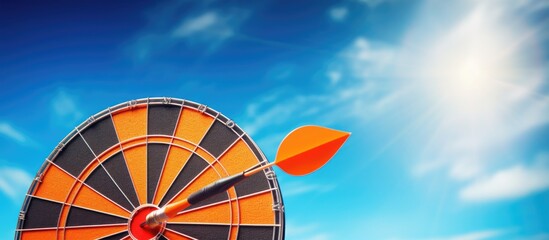 Wall Mural - A dart in the shape of an orange hits the bullseye in the center of a dartboard, against a blue sky background. This image represents concepts such as business, strategy, achievement, and planning.