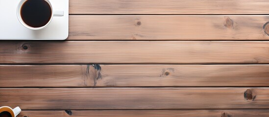 Poster - Top view of a wooden office desk with a smartphone showing a blank screen, a laptop computer, a cup of coffee, and supplies. is a flat lay with copy space.