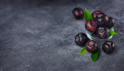 Wall Mural - Sweet plums on dark background. Fresh blue plums with leaves. Food fruit Background. Summer postcard. Harvesting in garden, Harvest of plum