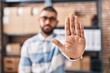 © Krakenimages.com - Young hispanic man ecommerce business worker doing stop gesture with hand at office