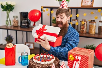 Poster - Young redhead man celebrating birthday unpacking gift at home