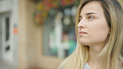 Poster - Young blonde woman looking to the side with serious expression at street