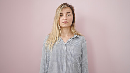 Wall Mural - Young blonde woman standing with serious expression over isolated pink background