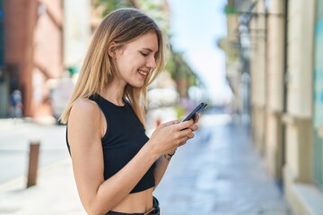 Poster - Young blonde woman using smartphone smiling at street