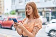 © Krakenimages.com - Young redhead woman smiling confident using smartphone at street