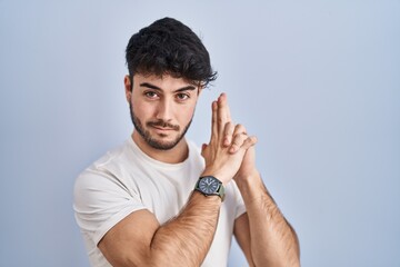 Poster - Hispanic man with beard standing over white background holding symbolic gun with hand gesture, playing killing shooting weapons, angry face