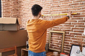 Wall Mural - Young hispanic man measuring wall at new home