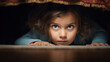 Little girl hiding under the bed with fear face 