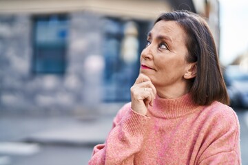 Wall Mural - Middle age woman standing with doubt expression at street