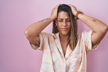 Poster - Blonde woman standing over pink background suffering from headache desperate and stressed because pain and migraine. hands on head.