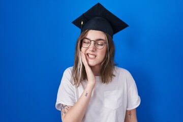 Poster - Blonde caucasian woman wearing graduation cap touching mouth with hand with painful expression because of toothache or dental illness on teeth. dentist