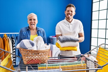 Wall Mural - Hispanic mother and son hanging clothes at clothesline sticking tongue out happy with funny expression.