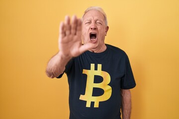 Sticker - Senior man with grey hair wearing bitcoin t shirt doing stop gesture with hands palms, angry and frustration expression