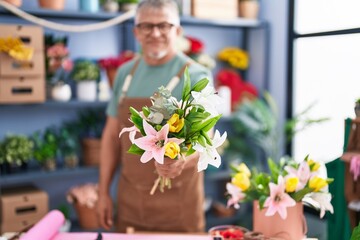 Wall Mural - Middle age grey-haired man florist holding bouquet of flowers at flower shop