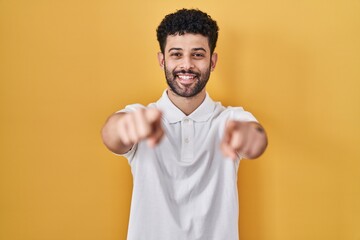 Poster - Arab man standing over yellow background pointing to you and the camera with fingers, smiling positive and cheerful