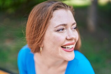 Wall Mural - Young redhead woman smiling confident looking to the side at park