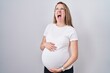 © Krakenimages.com - Young pregnant woman expecting a baby, touching pregnant belly angry and mad screaming frustrated and furious, shouting with anger looking up.