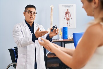 Poster - Young latin man pysiotherapist explaining hand press machine to patient at rehab clinic