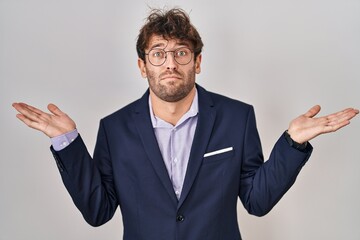 Canvas Print - Hispanic business man wearing glasses clueless and confused expression with arms and hands raised. doubt concept.