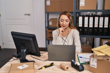 Wall Mural - Hispanic woman working at small business ecommerce wearing headset serious face thinking about question with hand on chin, thoughtful about confusing idea