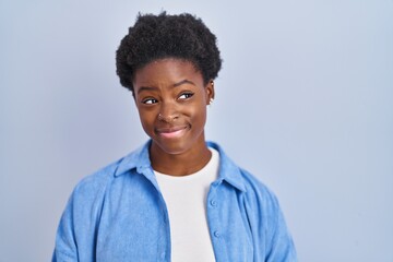 Sticker - African american woman standing over blue background smiling looking to the side and staring away thinking.