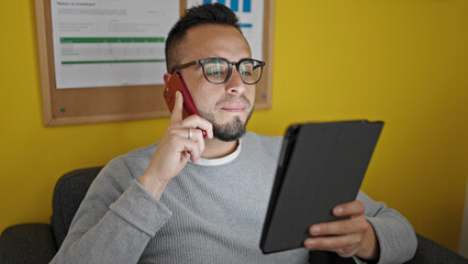 Poster - Hispanic man business worker using touchpad speaking on the phone at office