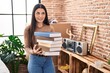 © Krakenimages.com - Young woman holding books at home smiling looking to the side and staring away thinking.