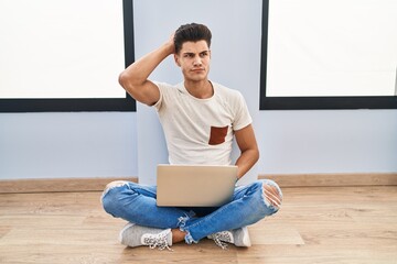 Sticker - Young hispanic man using laptop at home confuse and wondering about question. uncertain with doubt, thinking with hand on head. pensive concept.