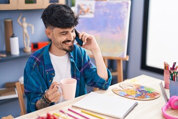 Sticker - Young hispanic man artist talking on smartphone drinking coffee at art studio