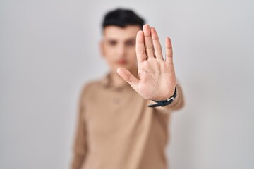 Poster - Non binary person standing over isolated background doing stop sing with palm of the hand. warning expression with negative and serious gesture on the face.