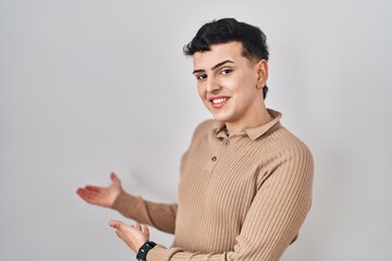 Wall Mural - Non binary person standing over isolated background inviting to enter smiling natural with open hand