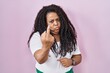 Plus size hispanic woman standing over pink background showing middle finger, impolite and rude fuck off expression
