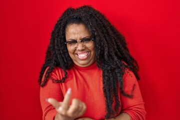 Sticker - Plus size hispanic woman standing over red background beckoning come here gesture with hand inviting welcoming happy and smiling