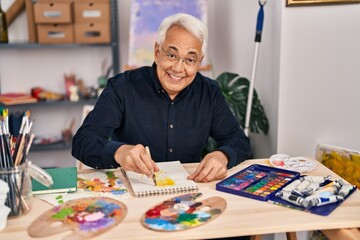 Wall Mural - Senior man smiling confident drawing on notebook at art studio