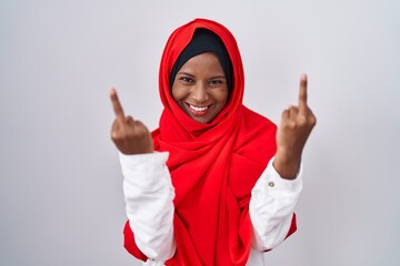 Wall Mural - Young arab woman wearing traditional islamic hijab scarf showing middle finger doing fuck you bad expression, provocation and rude attitude. screaming excited