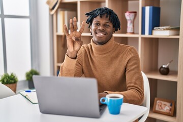 Sticker - Young african man with dreadlocks working using computer laptop showing and pointing up with fingers number four while smiling confident and happy.