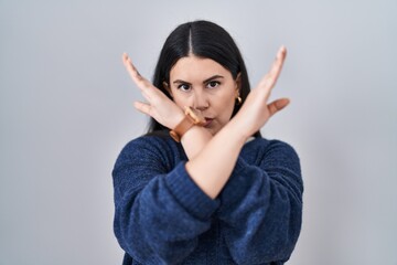 Canvas Print - Young brunette woman standing over isolated background rejection expression crossing arms doing negative sign, angry face