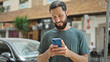 © Krakenimages.com - Young hispanic man using smartphone and earphones smiling at street