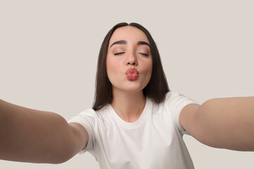 Sticker - Young woman taking selfie and blowing kiss on white background