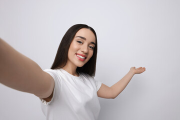 Sticker - Smiling young woman taking selfie on white background, space for text