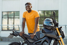 Smiling African American Man, Biker Looking At Camera And Posing Near Motorcycle