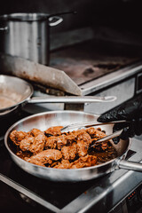 Wall Mural - woman chef cooking chicken wings in a sauce in the kitchen