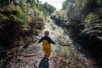 toddler exploring in yellow overalls in the forest